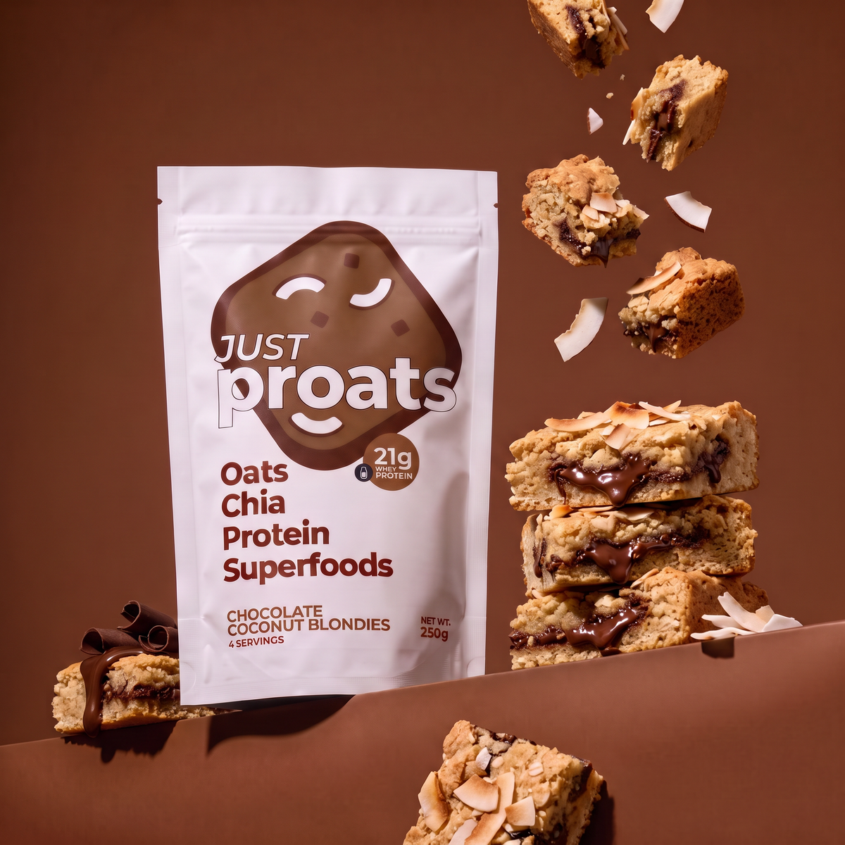 A stand-up pouch of Just Proats Oats Chia Protein Superfoods in Chocolate Coconut Blondies flavor, shown on a brown studio background with chocolate coconut blondies and coconut flakes floating around it.