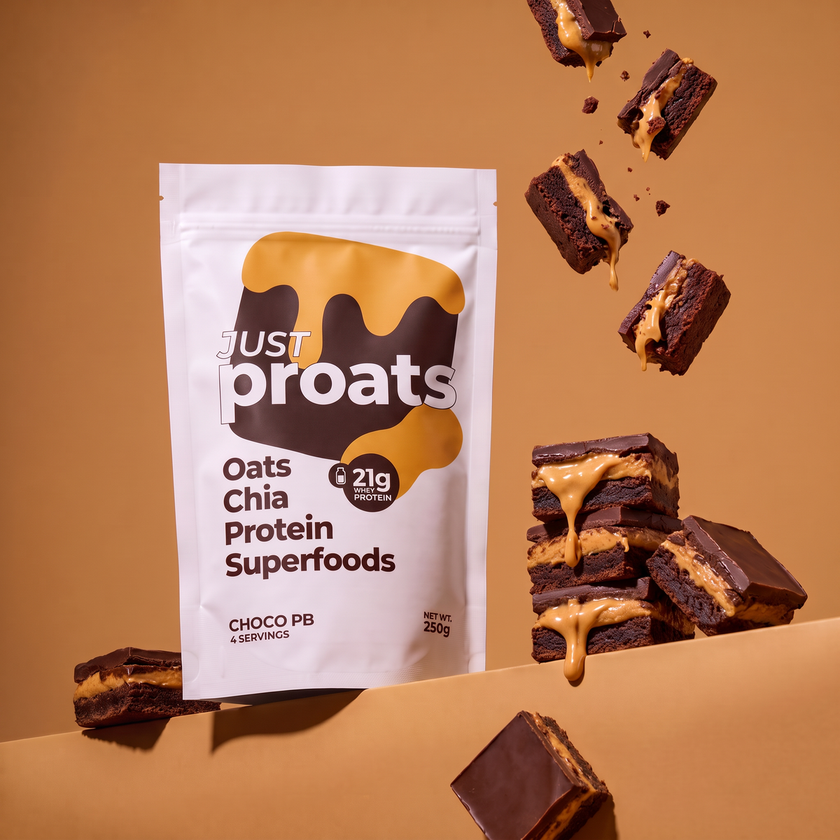 A stand-up pouch of Just Proats Oats Chia Protein Superfoods in Choco PB flavor, shown on a warm tan background with chocolate chip cookies and caramel-topped brownies floating around it.