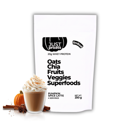 A white stand-up pouch of Just Proats 'Oats Chia Fruits Veggies Superfoods' protein powder, shown with a pumpkin spice latte and autumn spices in the foreground on a white background.